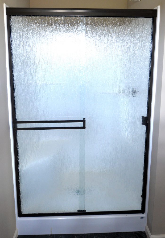 Frosted glass shower door with black metal accents